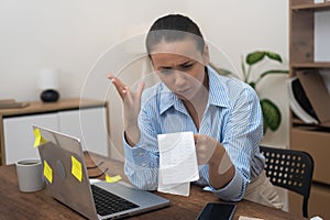 startled woman, homebound, financial stress, clutches a laptop, utility bill, and bank statements. photo