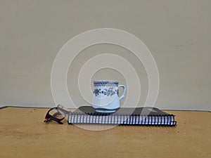 Picture of a tea cup,book and spectacles kept on a table