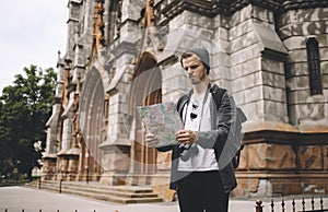 A picture of tourist standing near the big old building and looking to the map