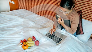 Picture of tourists used laptop and eating fruits on the bed in the luxury hotel room, healthy food concept