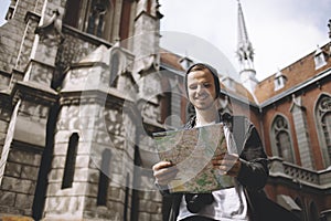 The picture of a traveller that is standing near the church. He is holding the map in his hands