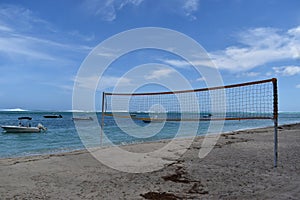 Picture of a tropical beach with beautiful colors, leisure boats in background and a volley ball net for leisure or some sport act