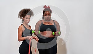 Picture of two afro women holding dumbbells and skipping rope, posing sexy