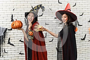 Picture of two emotional young women wearing witch halloween costumes on party over background decorated for Halloween