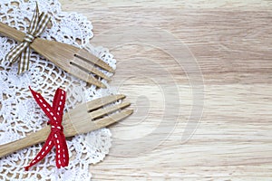 Picture of two forks with ribbon and white doily with wood background
