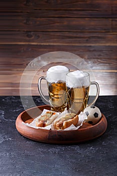 Picture of two mugs of beer and hot dogs on wooden tray