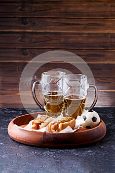 Picture of two mugs of beer and hot dogs on wooden tray