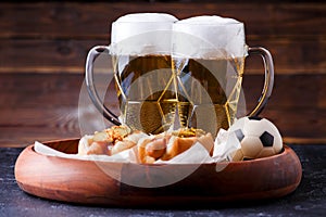 Picture of two mugs of beer and hot dogs on wooden tray