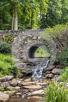 Waterfall under a stone bridge in a park