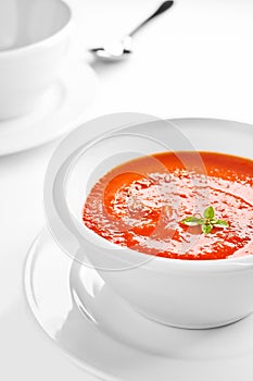 Picture of a white bowl with tomato cream soup.