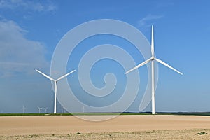 Picture of wind power towers located in a field and producing green energy.