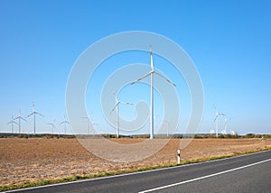 Picture of a wind turbine farm by a road against the blue sky