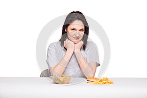 picture of woman with fruits and hamburger in front on white background, healthy versus junk food concept