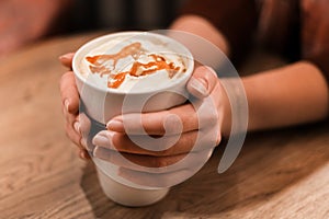 Picture of woman golding cup of coffee with caramel