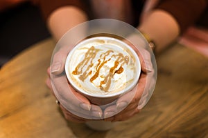 Picture of woman golding cup of coffee with caramel