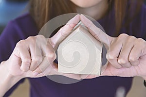 Picture of woman holding paper house model in her hands