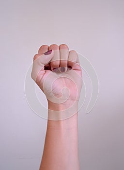 Woman raises fist feminist vindication with purple nails photo