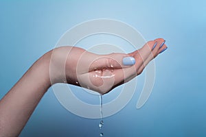 A picture of a woman`s hand on which water flows, on a blue background