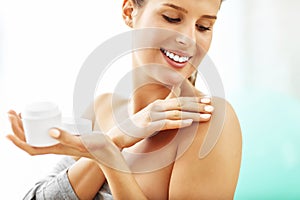 Woman using body lotion on her skin photo