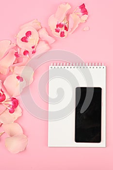 Picture for womens blog. Flat lay with flowers, notebook, smartphone and pencil on paper background