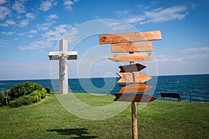 Picture of wooden direction signpost in front of the sea and grass