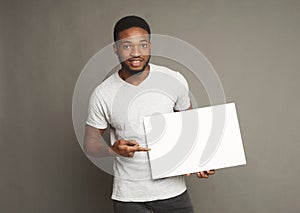 Picture of young african-american man holding white blank board