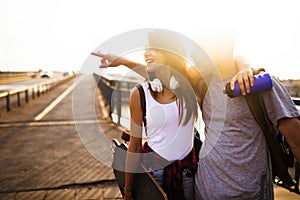 Picture of young attractive couple carrying skateboards