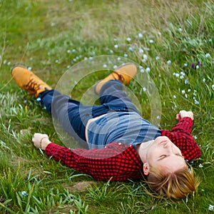 Picture of young beautiful blond man laying on green grass among