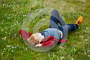 Picture of young beautiful blond man laying on green grass among