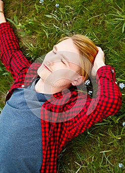 Picture of young beautiful blond man laying on green grass among