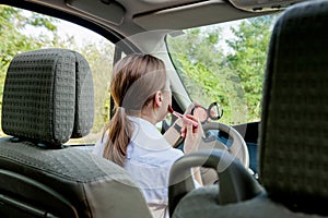 Picture of young businesswoman doing makeup while driving a car in the traffic jam