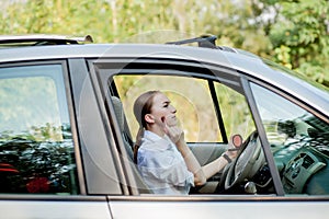 Picture of young businesswoman doing makeup while driving a car in the traffic jam