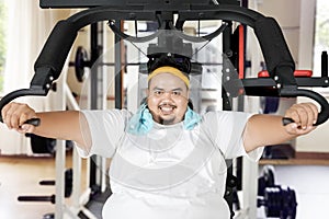 Smiling fat man exercises with a fitness machine