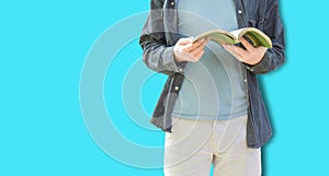 Picture of young man isolated over blue wall background holding book reading