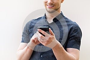 Picture of young man using a mobile smart phone and smiling