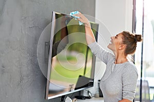 Picture of young woman cleaning tv screen