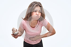 Picture of young woman hold eclair. She is going to puke. Model hold hand on stomach. She feels bad. Isolated on white