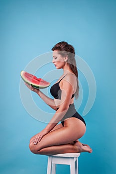 Picture of young woman holding a big slice watermelon in the studio