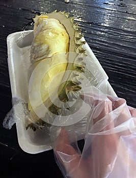 Pictured is a durian and a gloved hand.