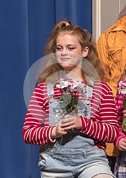 Eleven-year old girl standing holding flowers on stage in school play