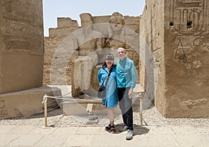 Tourist couple before the statue of the god Amun-Re and his wife Mut just before the Colonnade Hall in Luxor Temple, Egypt.