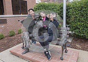 Family posing humorously with bronze of Will Rogers on a bench, Claremore, Oklahoma