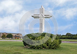 Ornate white wooden cross surrounded by green bushes in Plano, Texas. photo