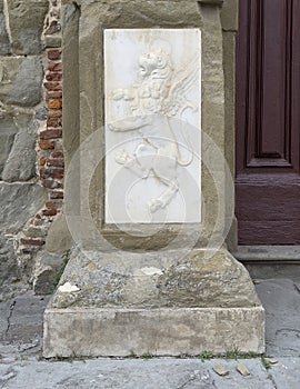 Relief of a winged lion in rampant position on the base of a pillar on the Cortona Cathedral in Cortona, Italy.