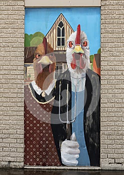 Chickens mimicking the farmer and his wife in the famous painting, American Gothic by Grant Wood.