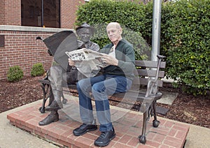 Seventy year-old man posing humorously with bronze of Will Rogers on a bench, Claremore, Oklahoma