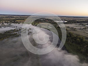 Pictures of the drone flight over the fog. River, forest, fields and meadows on a misty summer dawn. Summer