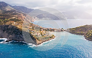 Picturesque aerial shot of colorful fishing Asos village houses on Cephalonia island, Greece. Steep cliff banks washed by blue