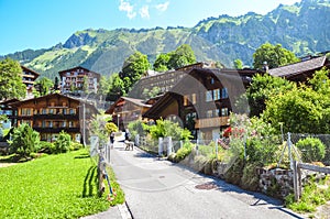 Picturesque Alpine village Wengen in Switzerland in summer season. Mountain chalets, hikers and green hilly landscape. Swiss Alps