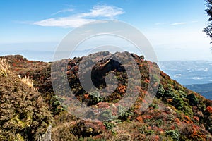 Picturesque autumn view of Unzen Nita Pass trail with rocky volcano peak, clear blue sky and colorful trees in Unzen-Amakusa. photo